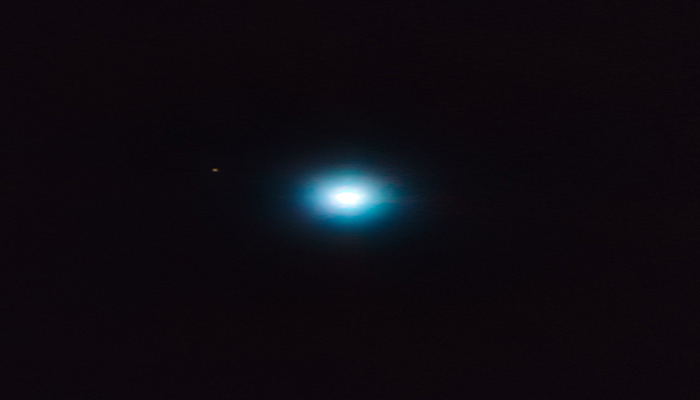 O exoplaneta, intitulado CVSO 30c, é o ponto marrom na parte esquerda da foto. A mancha brilhante central é sua estrela mãe.